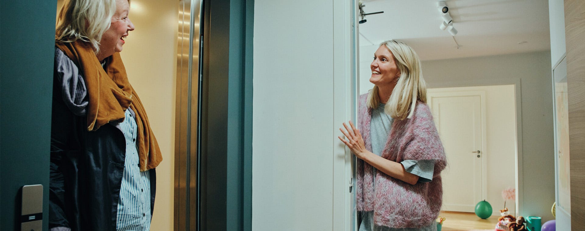 Zwei Frauen unterhalten sich im Hausflur von Wohnung zu Wohnung