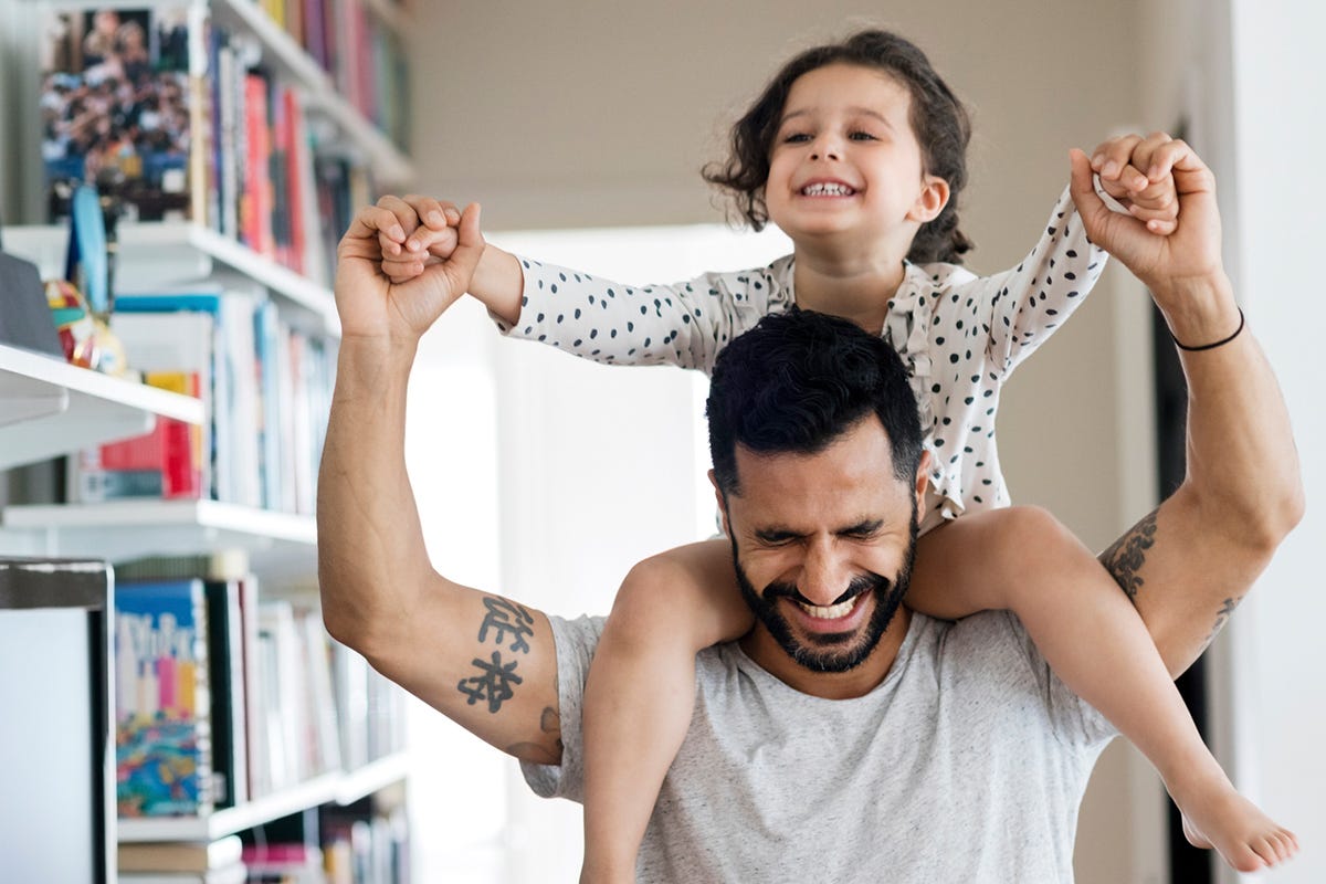 Ein Vater trägt seine Tochter auf den Schultern